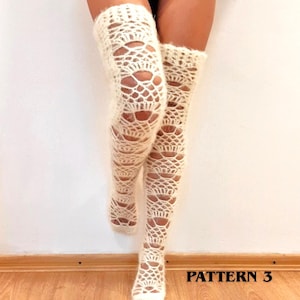 May include: A pair of off-white, over-the-knee crochet stockings featuring an intricate, open-work lace pattern with a fuzzy, textured yarn finish. The stockings extend from the feet up to the mid-thigh, displaying a repeating geometric design.