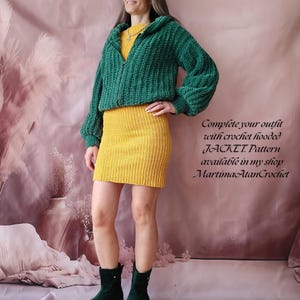 K&ouml;nnte beinhalten: Eine Frau tr&auml;gt eine gr&uuml;ne Kapuzenjacke aus H&auml;kelarbeit &uuml;ber einem gelben Kleid. Die Jacke hat einen Rei&szlig;verschluss und die &Auml;rmel sind lang und bauschig. Das Kleid ist kurz und gerippt. Der Text auf dem Bild lautet: "Complete your outfit with crochet hooded JACKET, Pattern available in my shop MartimaAtanCrochet."