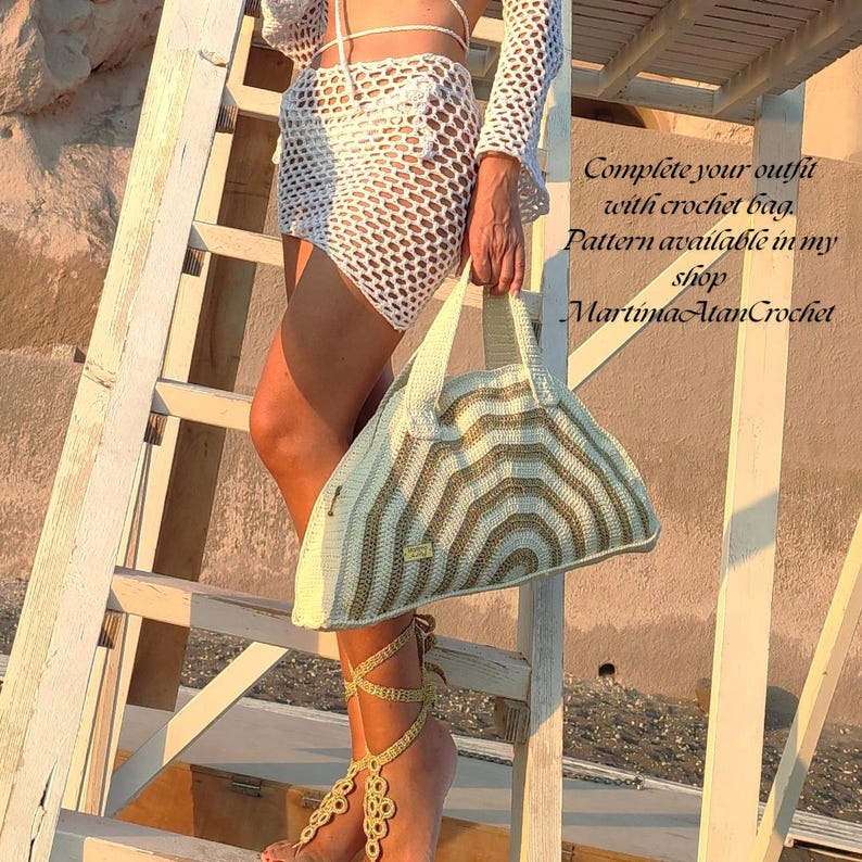 May include: A cream and gold crochet handbag with a semi-circular shape and two handles, featuring a striped pattern. The text on the image reads: Complete your outfit with crochet bag. Pattern available in my shop MartimaAtanCrochet.
