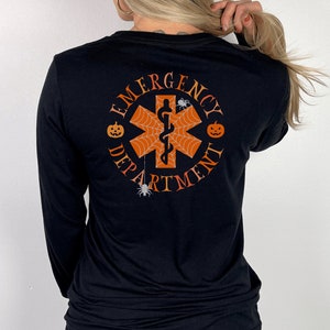May include: Black long-sleeve shirt with a Halloween-themed "Emergency Department" graphic featuring a red medical symbol with a spider web, pumpkins, and spiders.