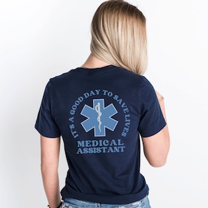 May include: A navy blue t-shirt with a white star of life graphic and the text "It's a good day to save lives Medical Assistant".