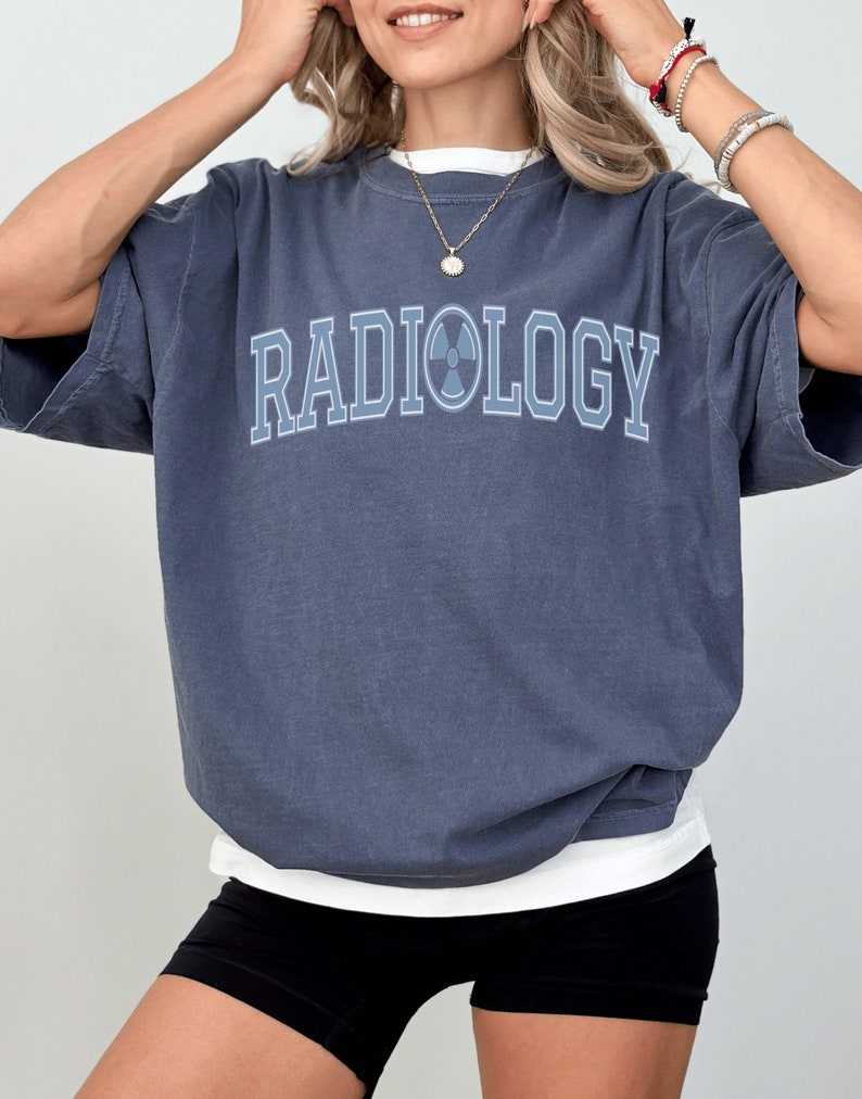May include: A dark blue t-shirt with the word "RADIOLOGY" printed in white with a blue outline and a radiation symbol in the middle of the word.
