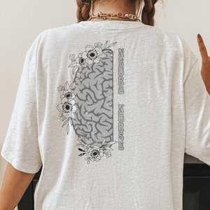 May include: White t-shirt with a gray brain graphic and floral design. The text "NEURO NURSE" is printed vertically on the right side of the brain.