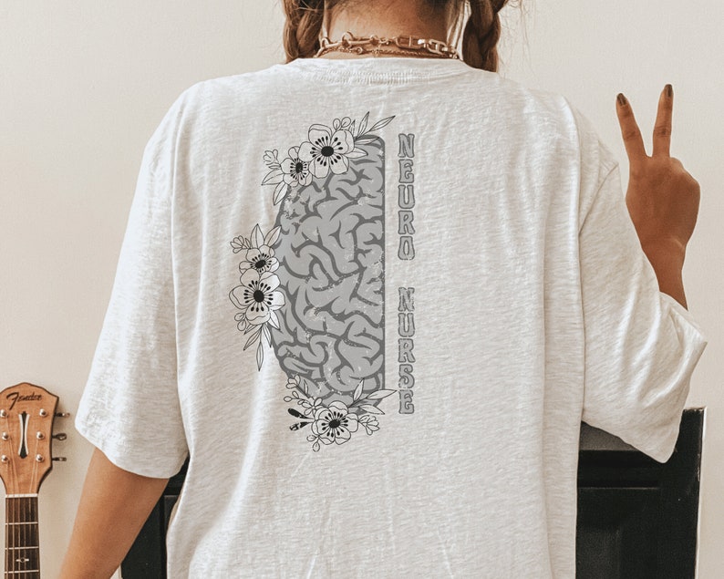 May include: White t-shirt with a gray brain graphic and floral design. The text "NEURO NURSE" is printed vertically on the right side of the brain.