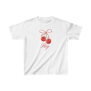 May include: White t-shirt with a red bow and two red cherries with the word "Big" printed below.