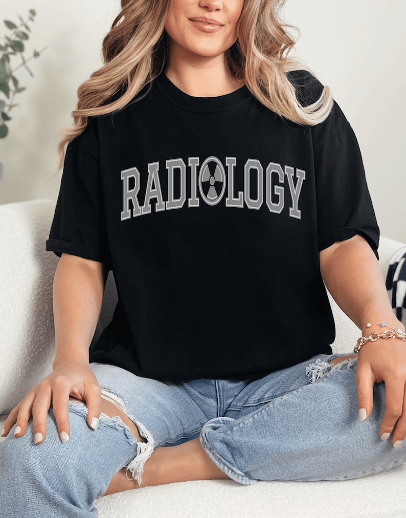 May include: Black t-shirt with the text "RADIOLOGY" in white with a gray radiation symbol in the middle of the word.