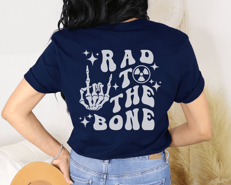 May include: Navy blue t-shirt with a white skeleton hand giving the middle finger, a radioactive symbol, and the text "Rad to the Bone" in a retro font.