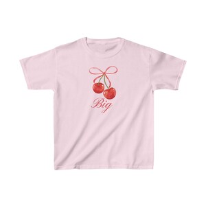 May include: Pink t-shirt with a graphic of two red cherries tied together with a pink ribbon. The text "Big" is written below the cherries.