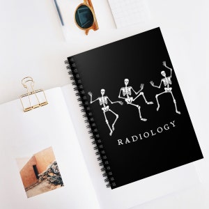 May include: Black spiral notebook featuring a white design of four skeletons dancing. The text "RADIOLOGY" is printed in white at the bottom of the notebook.