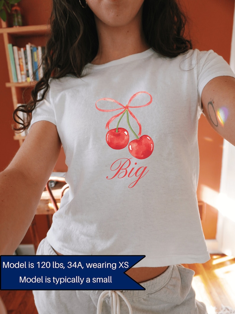 May include: White cropped t-shirt with a red cherry graphic and the word "Big" in pink lettering.