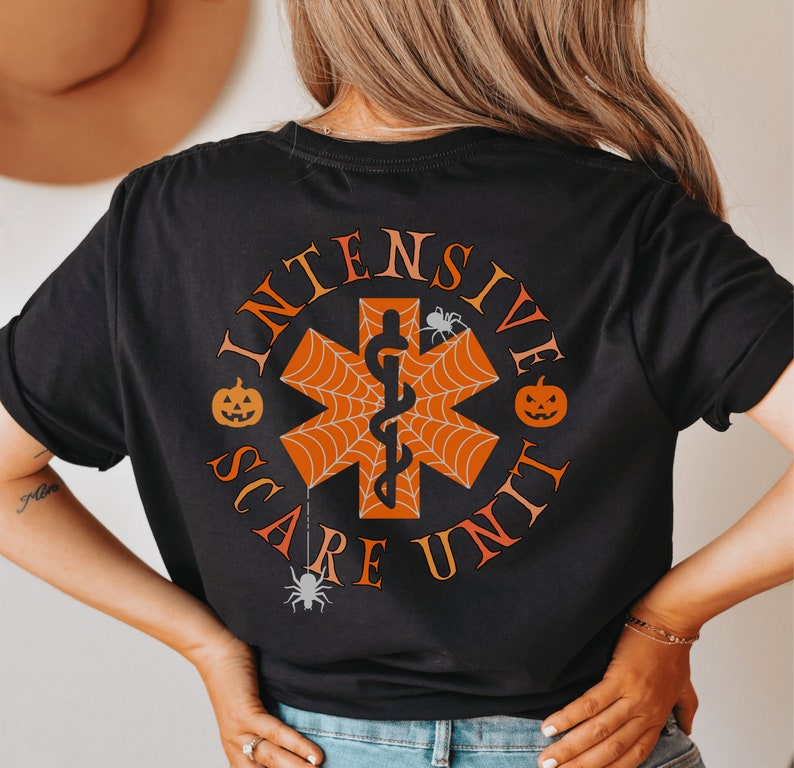 K&ouml;nnte beinhalten: Schwarzes T-Shirt mit einem Halloween-Motiv. Das Design zeigt einen roten und orangen medizinischen Stern des Lebens mit einer Schlange und einem Spinnennetz. Der Text "Intensive Scare Unit" umgibt den Stern des Lebens.
