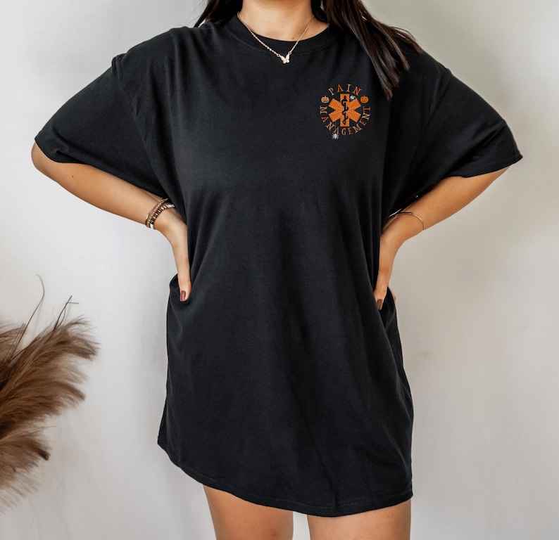 May include: Black oversized t-shirt with an orange graphic of a medical symbol and the text "Pain Management".