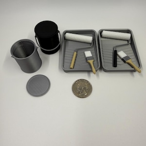 May include: A collection of miniature painting supplies, including two gray paint trays with rollers and brushes, two small buckets, and a coin. The black bucket has a handle. The paint rollers are white.
