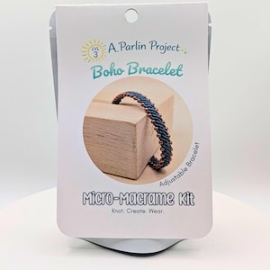 May include: A micro-macrame kit in white packaging featuring the text A. Parlin Project, Level 3, Boho Bracelet, Adjustable Bracelet, and Micro-Macrame Kit: Knot. Create. Wear. The center shows a dark blue braided bracelet with copper-colored beads.