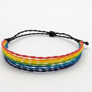 May include: A rainbow colored friendship bracelet with a black adjustable cord.