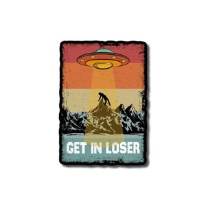 May include: A retro-style illustration of a UFO hovering over a mountain range with a person standing on top. The text "GET IN LOSER" is below the image.