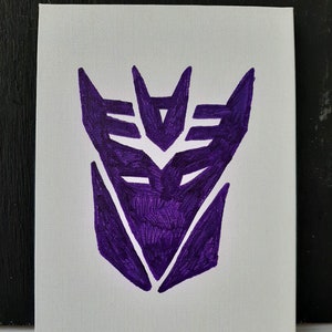 Pode incluir: Tela pintada de roxo com o símbolo dos Decepticons de Transformers.