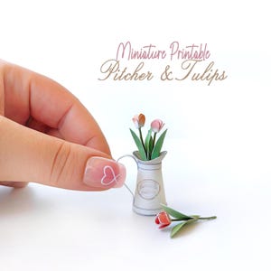 Puede incluir: Jarra y tulipanes imprimibles en miniatura. Una pequeña jarra blanca con asa contiene tulipanes de papel en tonos rosas y naranjas. Un solo tulipán yace junto a la jarra. El texto "Miniature Printable Pitcher & Tulips" está en la esquina superior derecha.