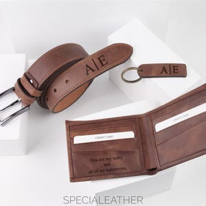 May include: A brown leather belt, wallet, and keyring set. The belt and keyring are engraved with the initials "A|E". The open wallet displays credit card slots and an engraved message. The text "SPECIALLEATHER" is at the bottom.
