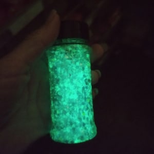 May include: A glass jar filled with green and white glitter that glows in the dark.