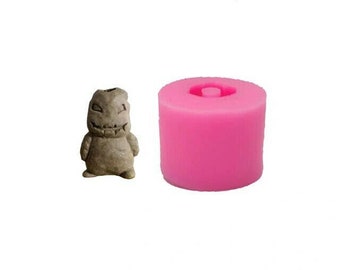 May include: A pink silicone mold for making a small, detailed figurine of a monster with a toothy grin. The mold is cylindrical and has a hole in the top for pouring.