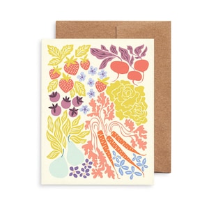 May include: A greeting card with a colorful illustration of various garden vegetables and fruits, including strawberries, blueberries, carrots, and pears. The card is cream-colored with a brown envelope.