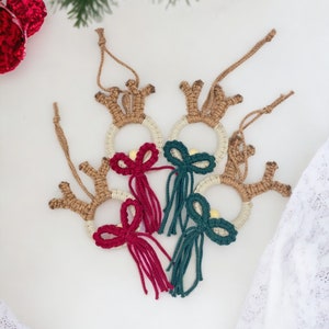 May include: Three handmade crocheted reindeer ornaments with brown antlers, white and beige yarn circles, and red and green yarn bows with tassels.