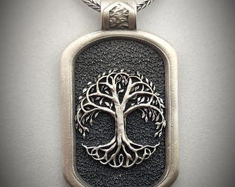 May include: A silver pendant necklace with a tree of life design. The pendant is rectangular with a textured black background and a silver tree of life design.