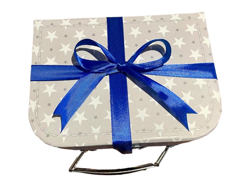 May include: A small, grey gift box patterned with white stars, tied with a bright blue ribbon and bow. The box has a silver handle, suitable for various occasions.