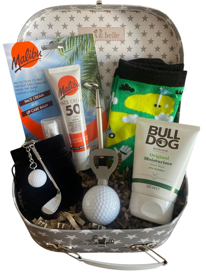 May include: A golf-themed gift set in a star-patterned case. Contents include sunscreen, lip balm, a golf ball keyring, a golf club pen, a golf ball bottle opener, golf socks, and Bulldog moisturiser. The moisturiser is 100 ml.