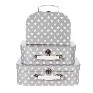 May include: A set of three decorative storage suitcases in varying sizes. The suitcases are gray with a white star pattern. Each suitcase has a white handle and silver-colored metal clasps.