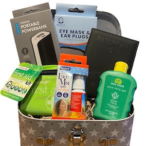 May include: A travel gift set containing a portable power bank, eye mask and ear plugs, a passport, aloe vera gel, a first aid kit, and face mist spray. The basket is grey with white star pattern.
