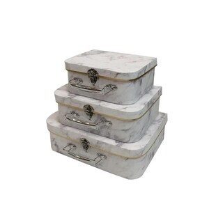 May include: Three decorative storage boxes with a marble effect pattern, stacked on top of each other. Each box has a silver handle and clasp, with a gold trim. The boxes are rectangular with rounded corners, in descending size.