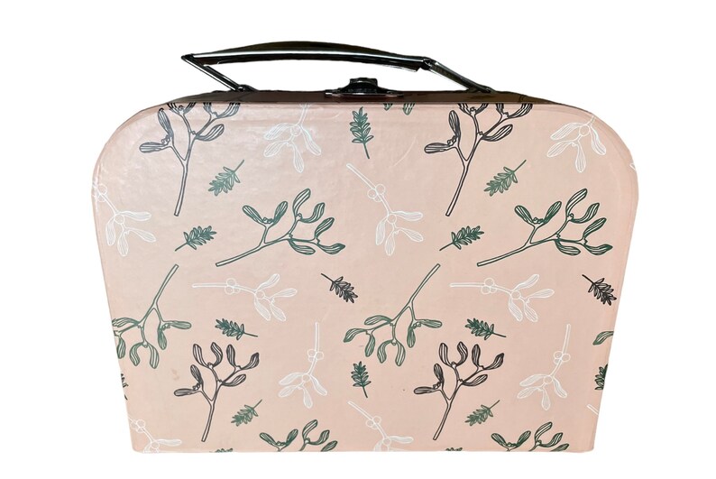 May include: A blush-colored suitcase with a black handle and clasp. The suitcase is decorated with a repeating pattern of mistletoe and leaf illustrations in shades of green and white. The suitcase has a rounded top and bottom.