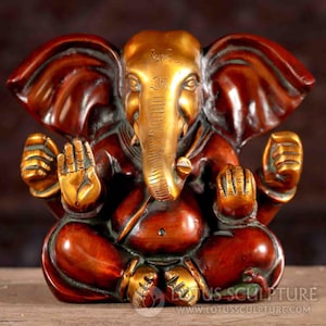 Puede incluir: Una estatua de bronce dorada y roja de Ganesha, el dios hind&uacute; de los comienzos, la sabidur&iacute;a y la prosperidad. La estatua representa a Ganesha sentado con la trompa levantada y las manos en un gesto mudra. La estatua est&aacute; decorada con intrincados detalles y es un hermoso ejemplo de la artesan&iacute;a tradicional india.