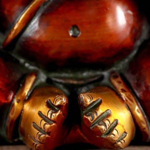 Puede incluir: Primer plano de una estatua dorada de Ganesha con intrincados detalles en las manos y los pies. La estatua est&aacute; hecha de lat&oacute;n y tiene una p&aacute;tina marr&oacute;n rojiza.