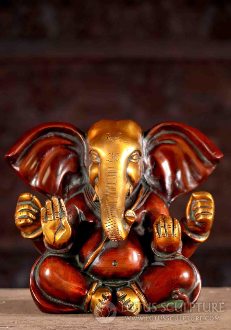 Puede incluir: Una estatua de bronce dorada y roja de Ganesha, el dios hind&uacute; de los comienzos, la sabidur&iacute;a y la prosperidad. La estatua representa a Ganesha sentado con la trompa levantada y las manos en un gesto mudra. La estatua est&aacute; decorada con intrincados detalles y es un hermoso ejemplo de la artesan&iacute;a tradicional india.