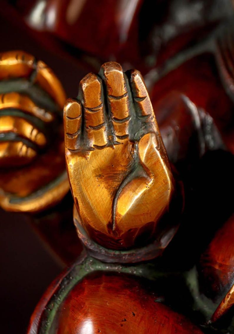 Puede incluir: Primer plano de una mano dorada con tallas detalladas, parte de una estatua m&aacute;s grande. La mano est&aacute; levantada con los dedos extendidos, lo que sugiere un gesto de bendici&oacute;n o protecci&oacute;n.