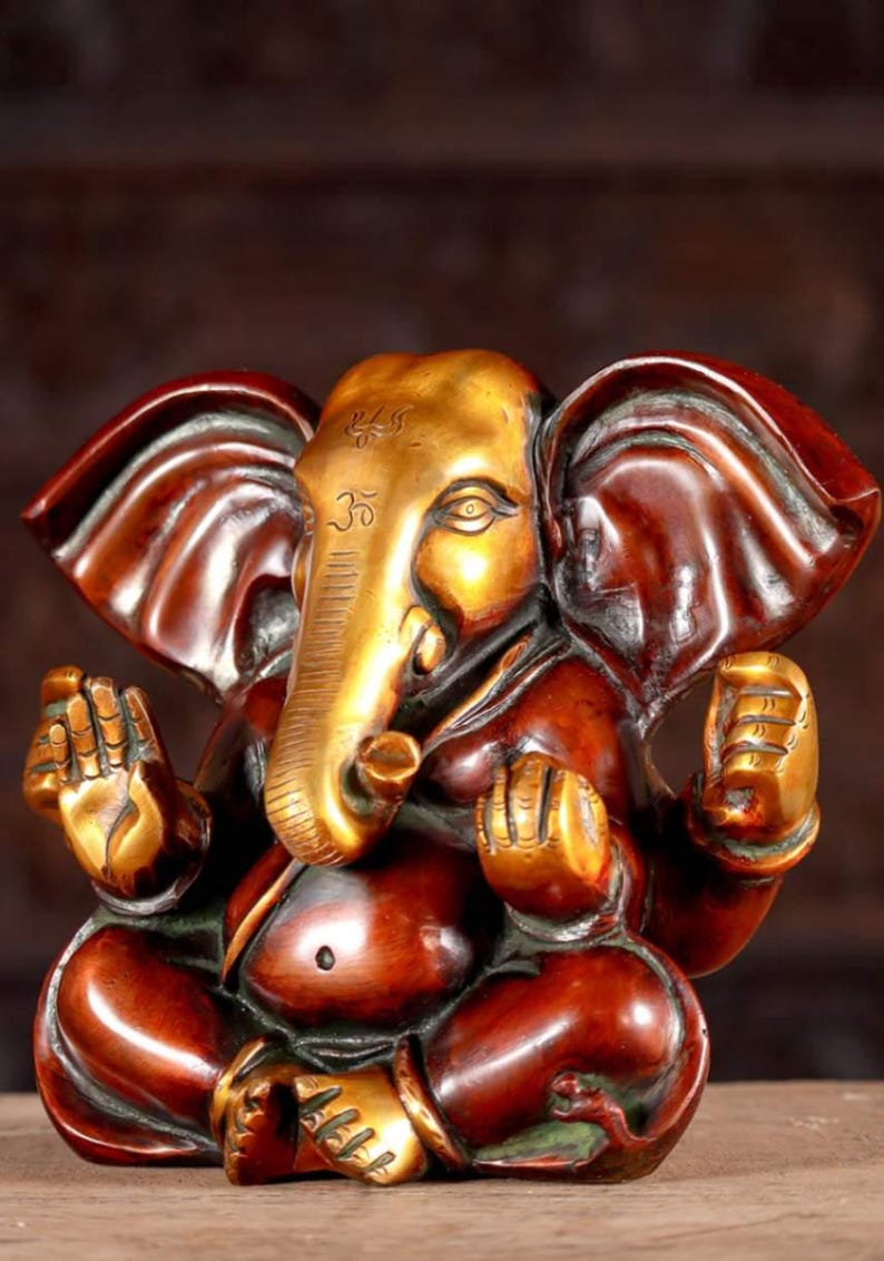 Puede incluir: Una estatua de bronce dorada y roja de Ganesha, el dios hind&uacute; de los comienzos, la sabidur&iacute;a y la prosperidad. La estatua representa a Ganesha sentado con la trompa levantada y las manos en un gesto mudra.