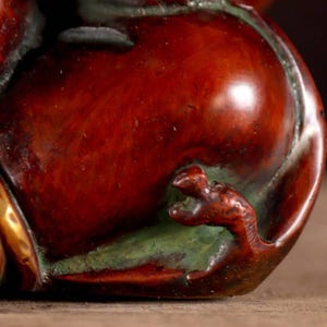 Puede incluir: Primer plano de una escultura de cer&aacute;mica roja, marr&oacute;n y verde de un drag&oacute;n. La cola del drag&oacute;n se envuelve alrededor del cuerpo de la escultura, y sus garras son visibles.