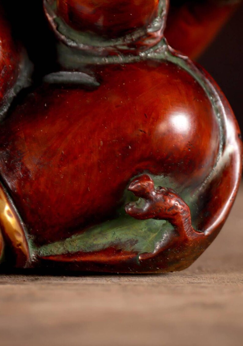 Puede incluir: Primer plano de una escultura de cer&aacute;mica roja, marr&oacute;n y verde de un drag&oacute;n. La cola del drag&oacute;n se envuelve alrededor del cuerpo de la escultura, y sus garras son visibles.