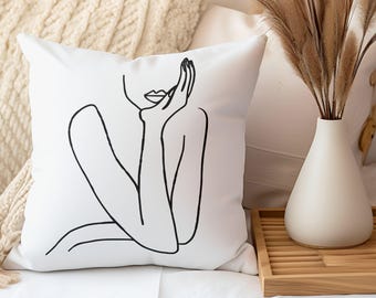 May include: White throw pillow with a black line drawing of a person's face and shoulders. The person is looking to the side and has their hand on their chin.
