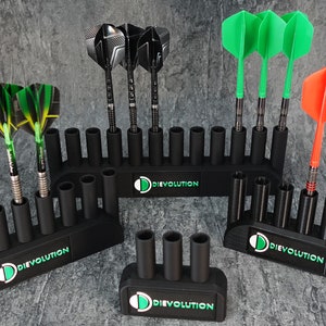 Könnte beinhalten: Drei schwarze Dart-Halter mit dem aufgedruckten Logo "Dievolution". Jeder Halter hat mehrere Steckplätze für Darts. Die Halter halten verschiedene farbige Darts, darunter grüne, schwarze und orange.