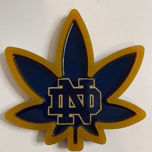 May include: A gold and blue resin leaf with the letters "ND" in gold inside.