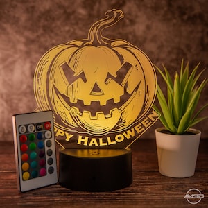 May include: A 3D printed, illuminated pumpkin-shaped night light with a carved jack-o'-lantern face and the text "Happy Halloween". The light is on a black base and has a remote control with multiple color options.