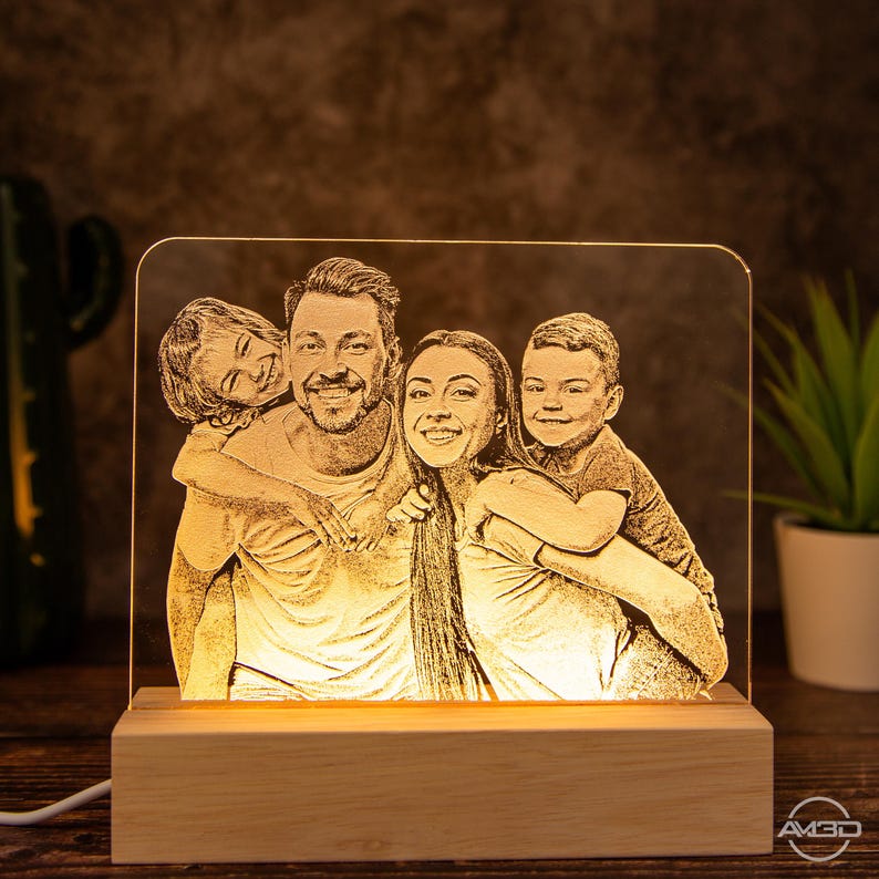 Peut inclure: Une veilleuse LED personnalis&eacute;e avec une base en bois. La lumi&egrave;re pr&eacute;sente un portrait de famille d'un homme, d'une femme et de deux enfants. L'image est grav&eacute;e dans le panneau acrylique et &eacute;clair&eacute;e par derri&egrave;re.