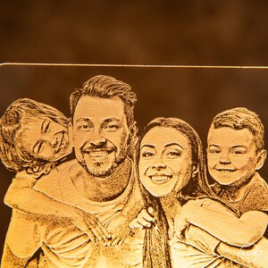 Peut inclure: Une image grav&eacute;e en or d'une famille de quatre personnes, dont un homme, une femme et deux enfants. La famille sourit et semble heureuse.
