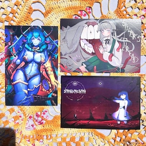 May include: Three art prints with anime-style illustrations. One shows a blue-skinned figure with horns. Another depicts a girl with a monster, and the text "SPIDER'S THREAD". The third print has a dark landscape and a figure.