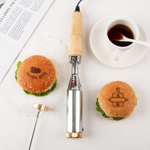 May include: A branding iron with a wooden handle and metal head, next to two sesame seed hamburger buns with the text "JASEN BBQ" and "A K" branded on them. A cup of coffee and a spoon are also in the image.