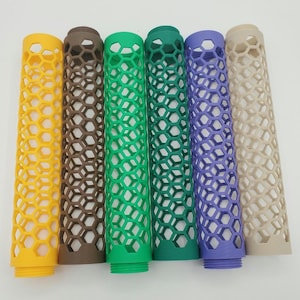 May include: Six cylindrical objects with a honeycomb pattern in yellow, brown, green, dark green, purple, and beige. The objects have a threaded base and are made of plastic.